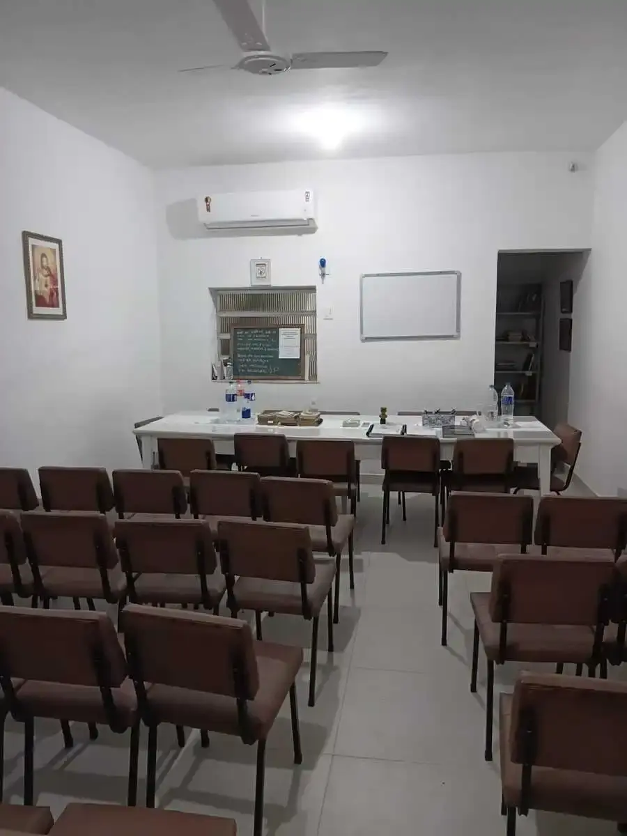 Sala do Centro Espírita Deus, Luz e Fé, com fileiras de cadeiras e uma mesa com livros